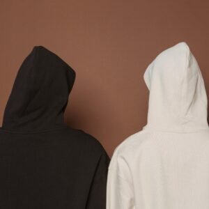 Back view of two hoodies in white and black against a brown background.