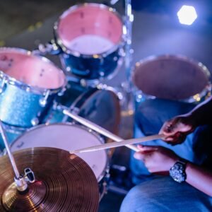 Musician performing on drum set with focus on hands and drum sticks.